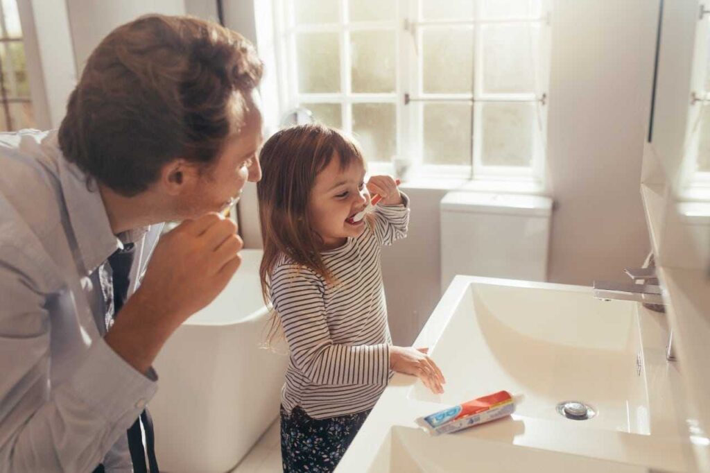 girl brushing her teeth with her dad Creekside Dental