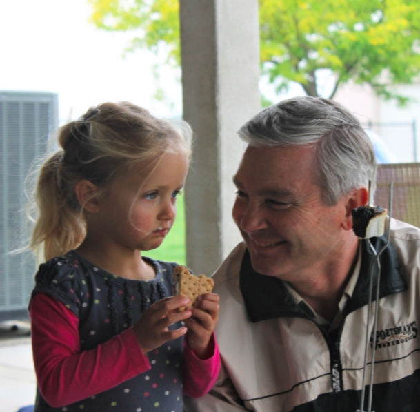 Dr. Floyd with his granddaughter holding a smores Creekside Dental