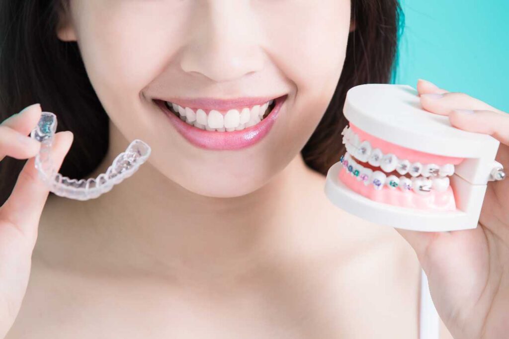 woman holding an invisalign and traditional braces Creekside Dental