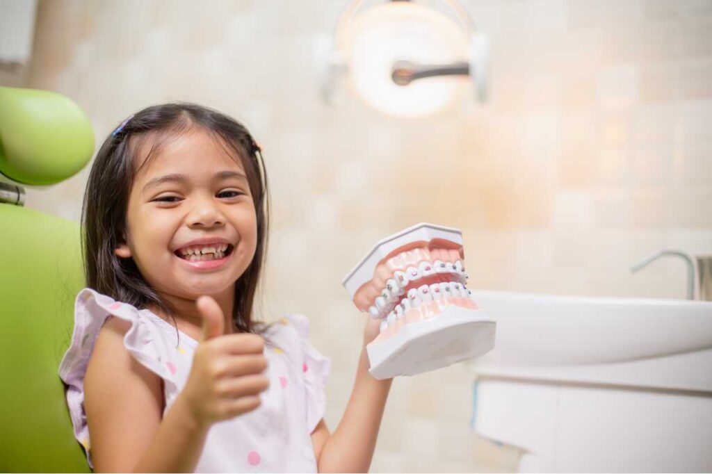little girl holding a sample teeth common misconceptions for orthodontic treatment Creekside Dental