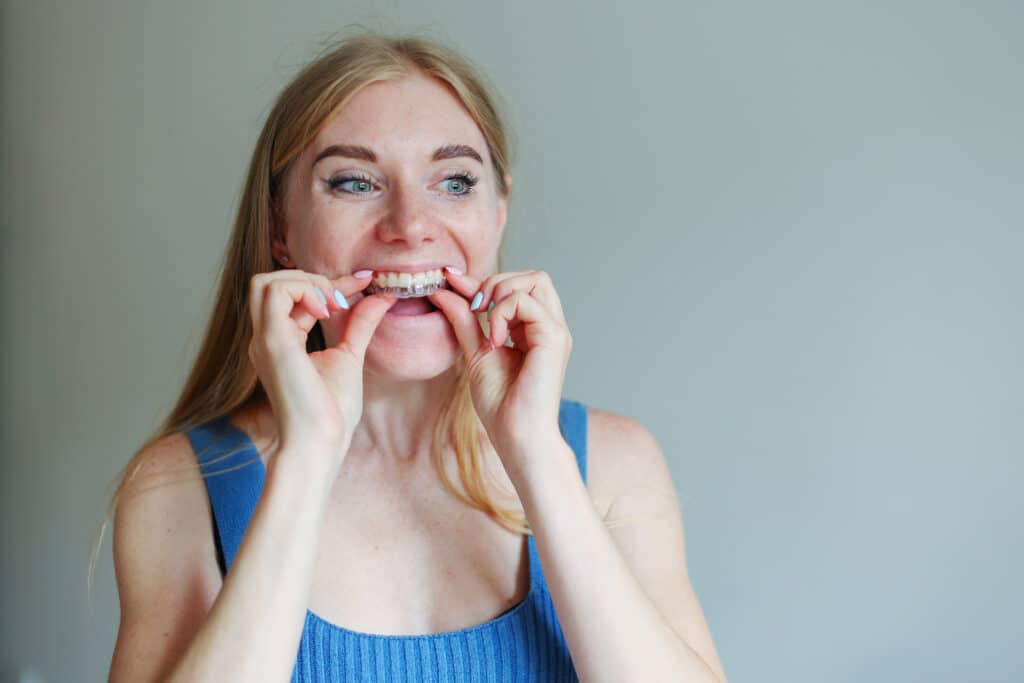 Woman wearing orthodontic silicone trainer. Invisible braces aligner. Mobile orthodontic appliance for dental correction.